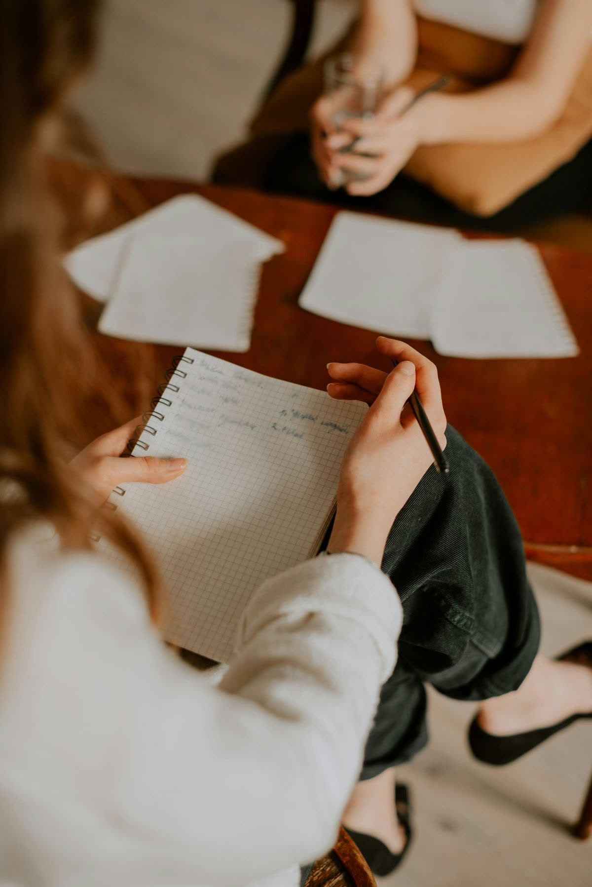 Sessão de psicoterapia vista de cima: a psicóloga faz anotações em um caderno enquanto ouve a paciente